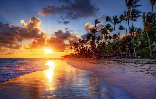 sunset over a palm fringed beach in the maldives