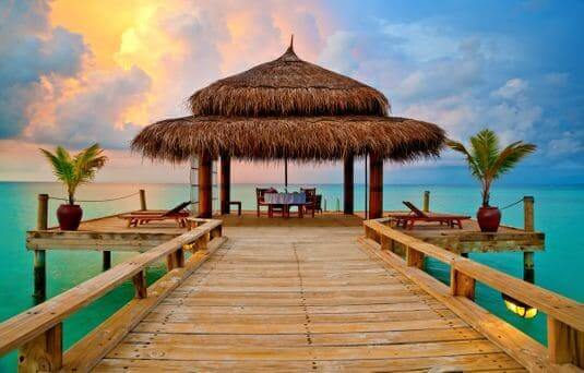 sunset over a tropical overwater hut in the maldives